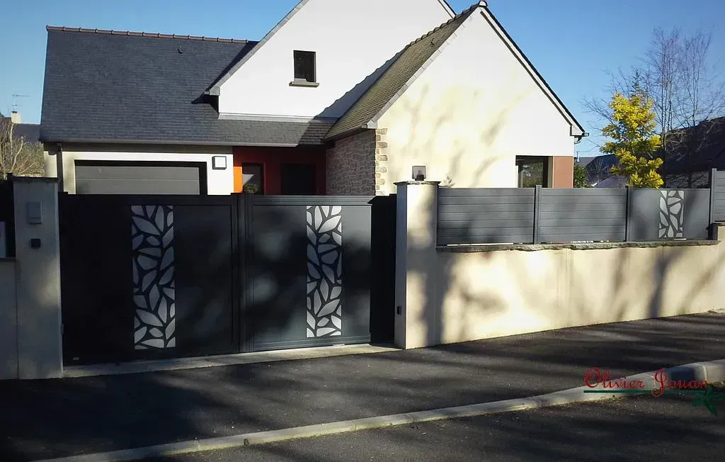 Maison moderne avec portail noir et mur beige, située dans une rue calme.