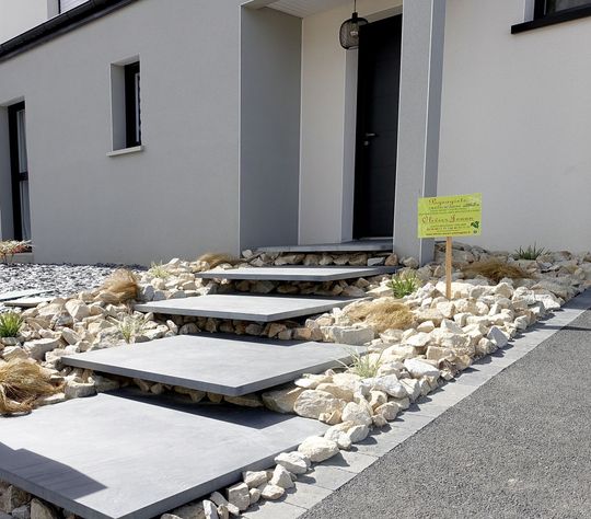 Entrée de maison moderne avec pas japonais, aménagement paysager en gravier et un petit panneau jaune près de la porte.