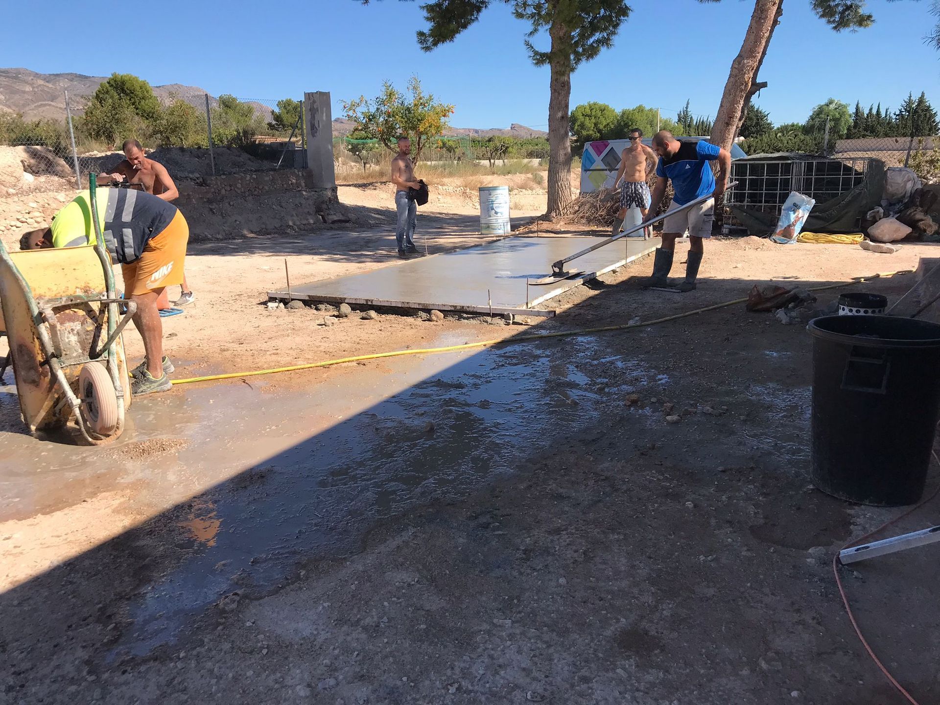Un grupo de trabajadores de la construcción está trabajando en un piso de concreto.