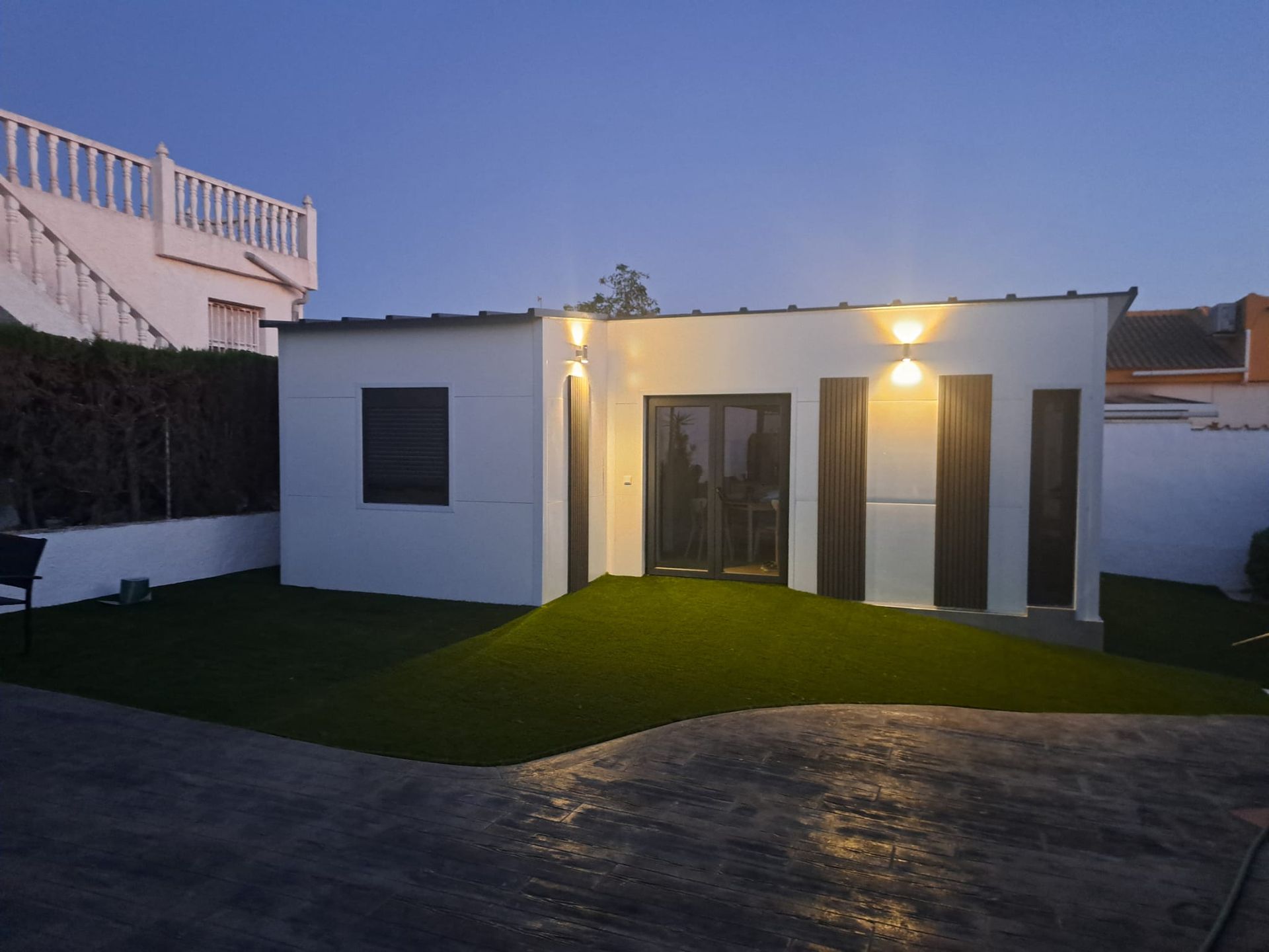 Una pequeña casa blanca está iluminada por la noche.