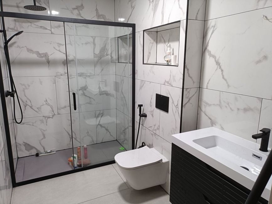Un baño con lavabo, inodoro, ducha y espejo.