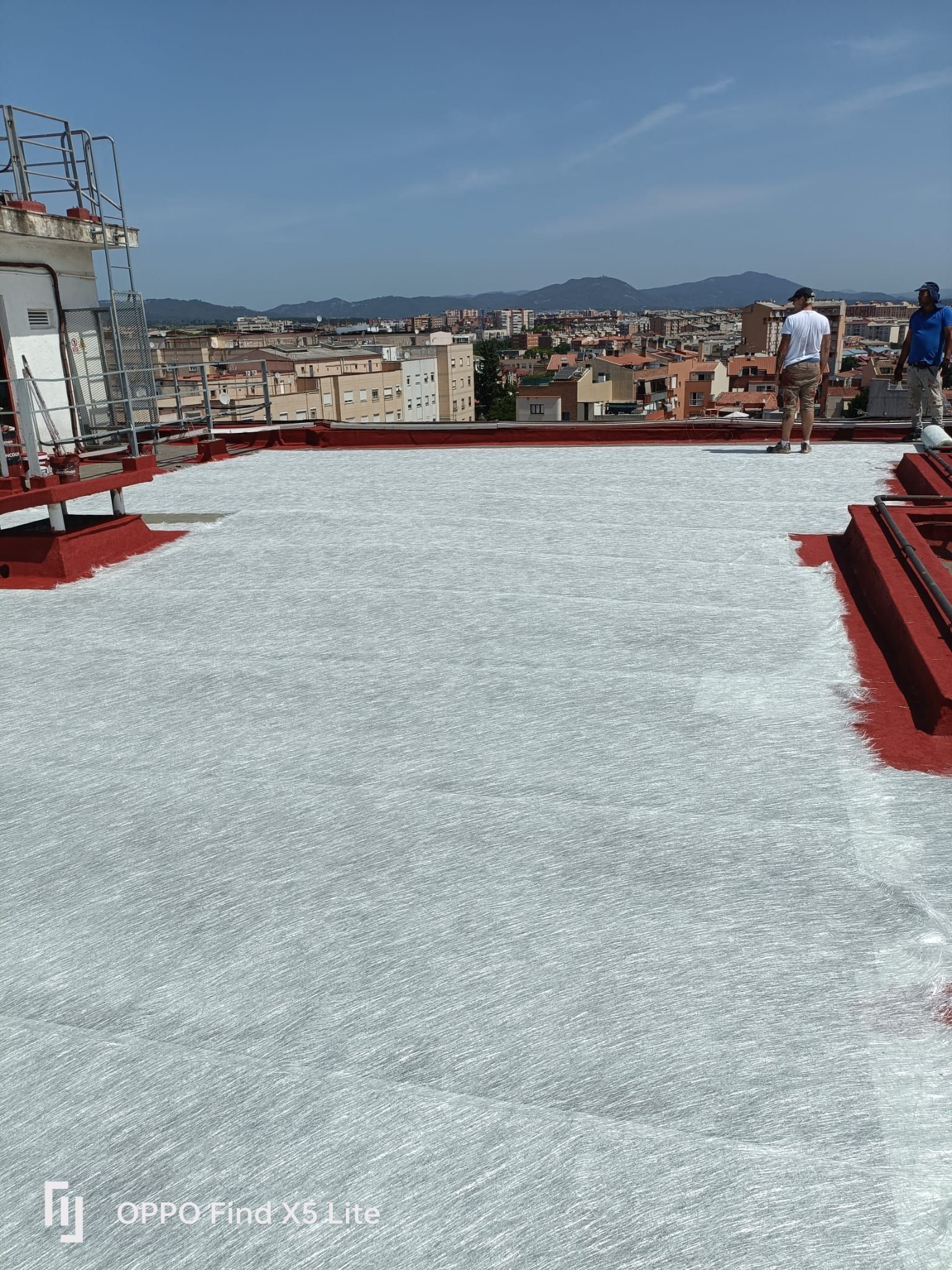 Dos hombres están de pie sobre un tejado con una ciudad al fondo.