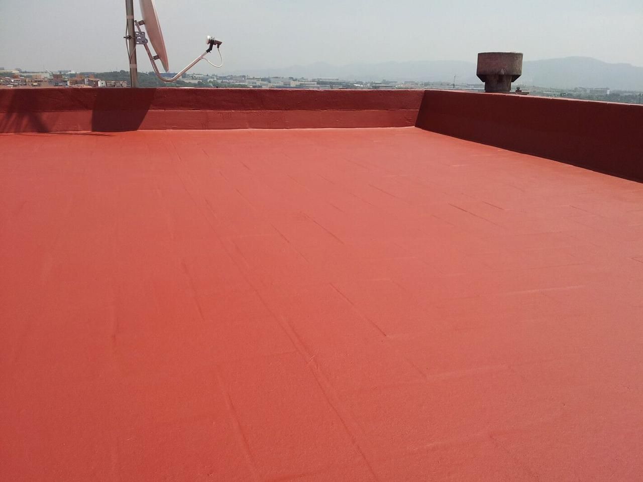 Un techo rojo con una antena parabólica encima.