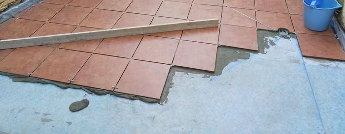Una persona está colocando baldosas en un piso de concreto.