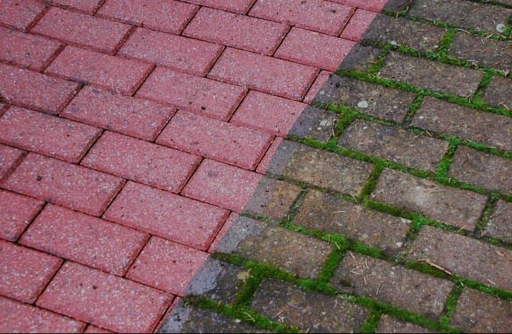 Rote Backsteinpflaster, zur Hälfte gereinigt, zeigen deutliche Farbunterschiede, und grüner Bewuchs wurde entfernt.