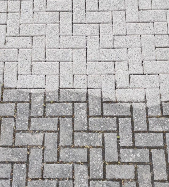 Graue Ziegelpflasterung, halb sauber, halb schmutzig, im Fischgrätmuster angeordnet.