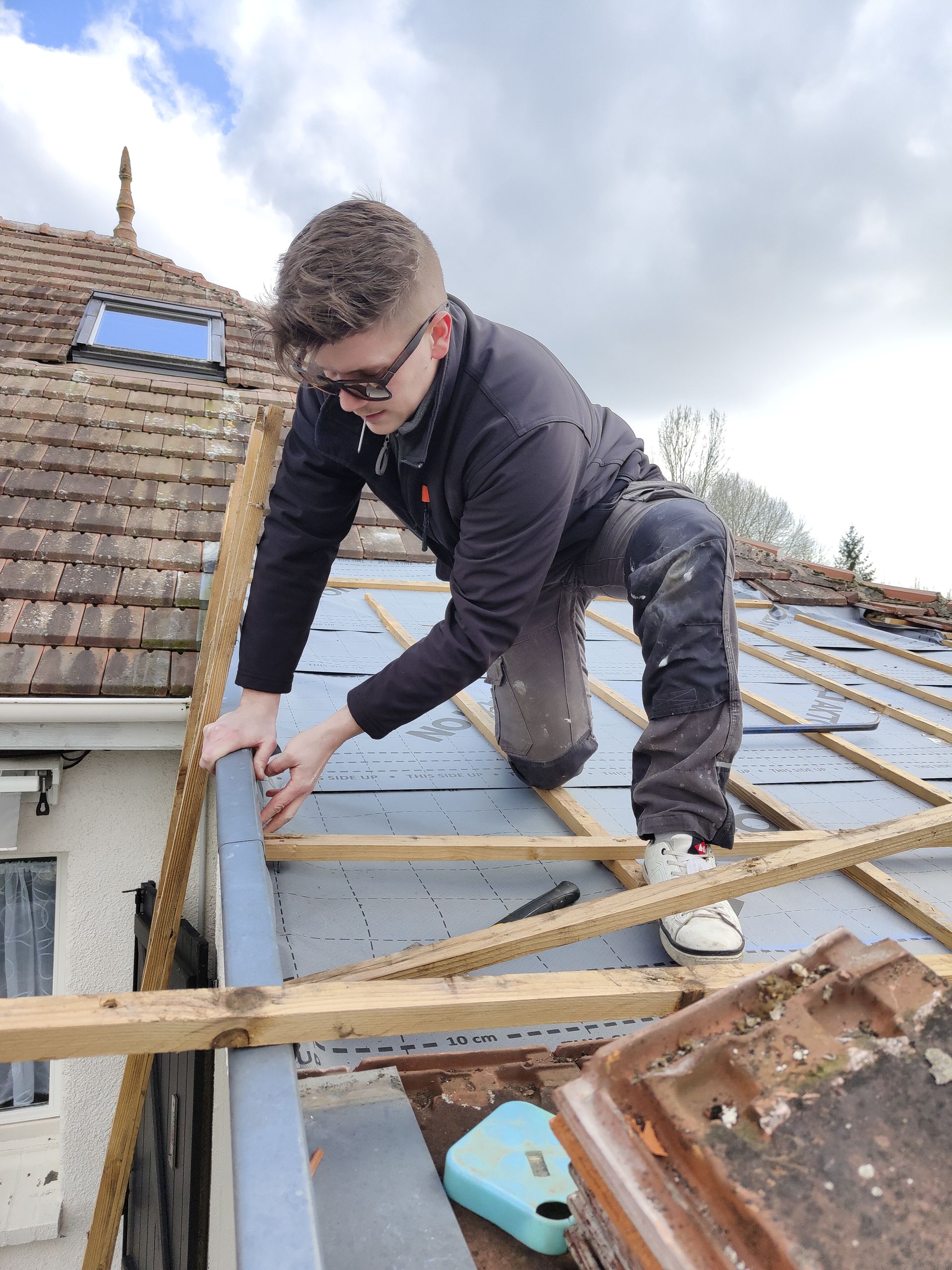 Un homme travaille sur le toit d'une maison.