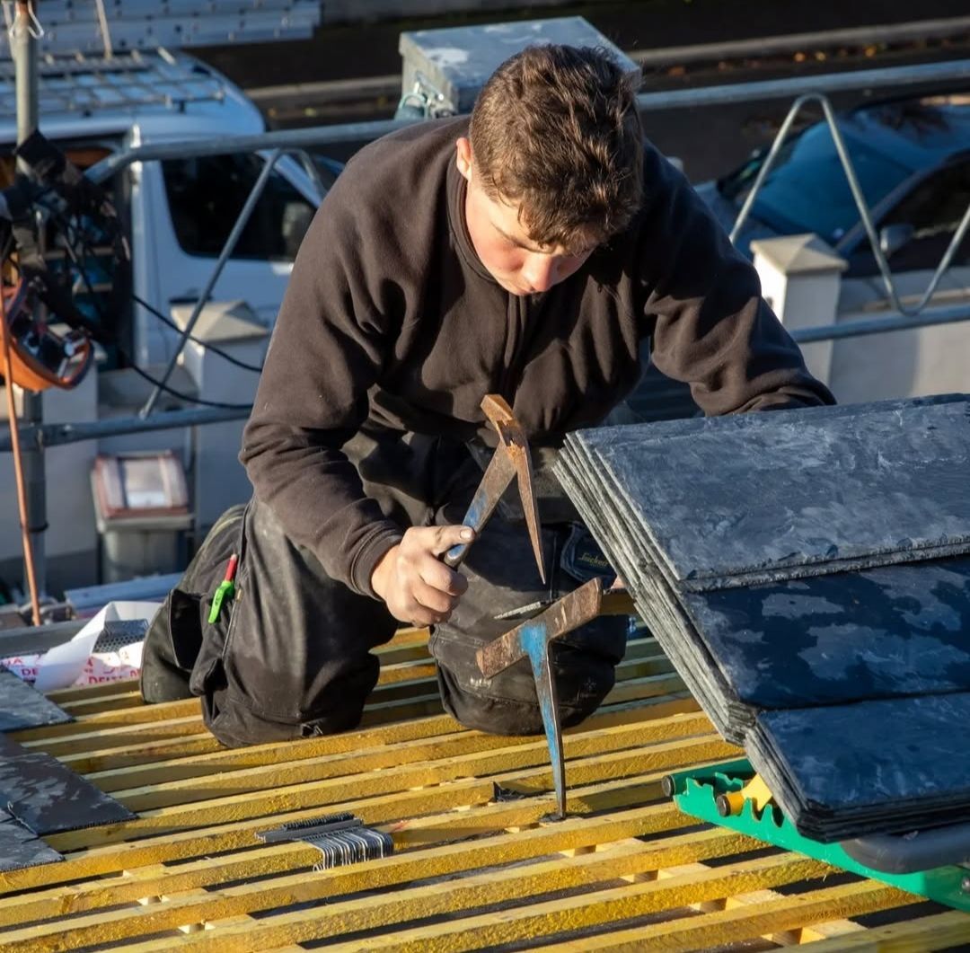 Un homme travaille sur un toit avec un marteau