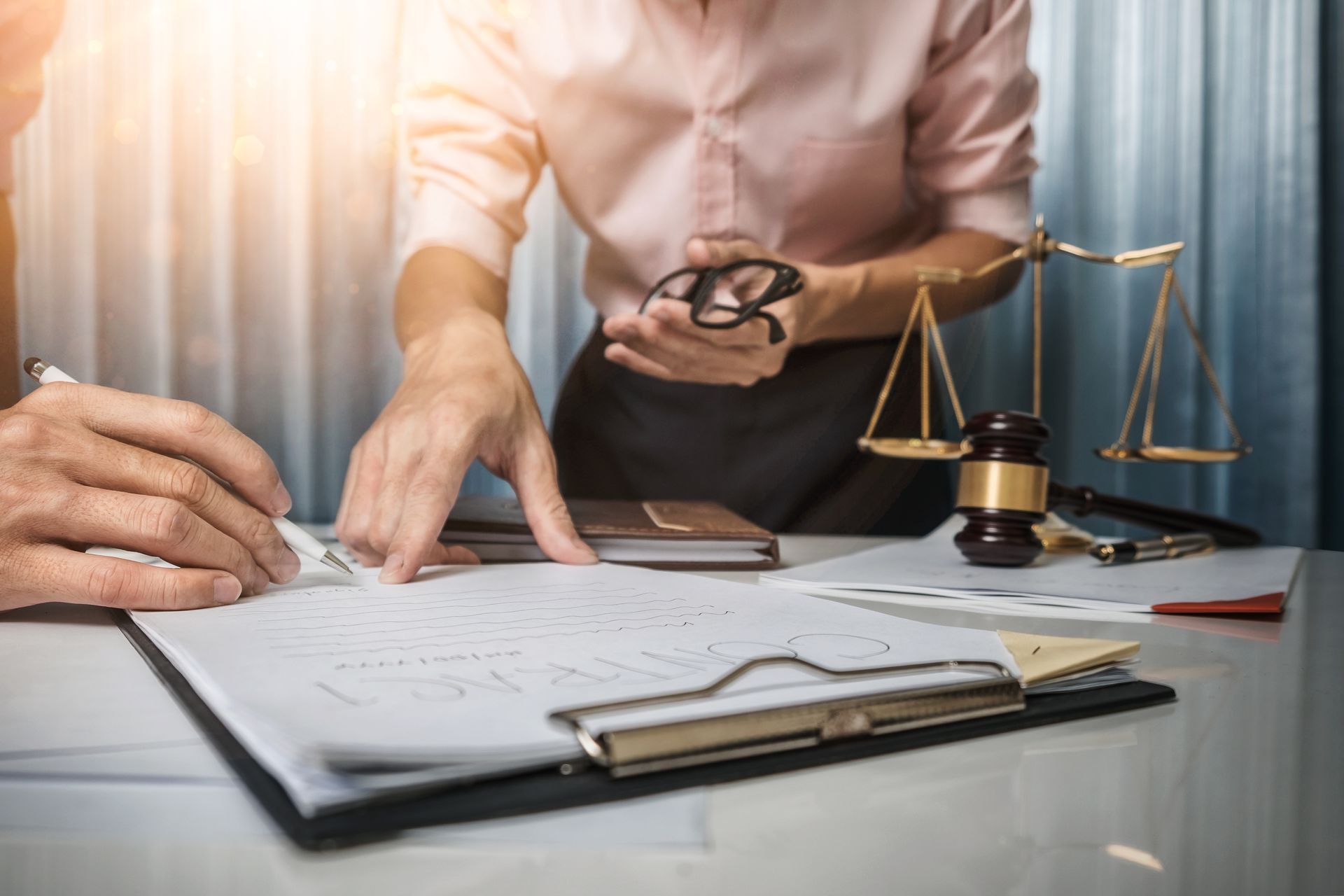 Un avocat examine des documents à son bureau, avec une balance de la justice et des lunettes à proximité