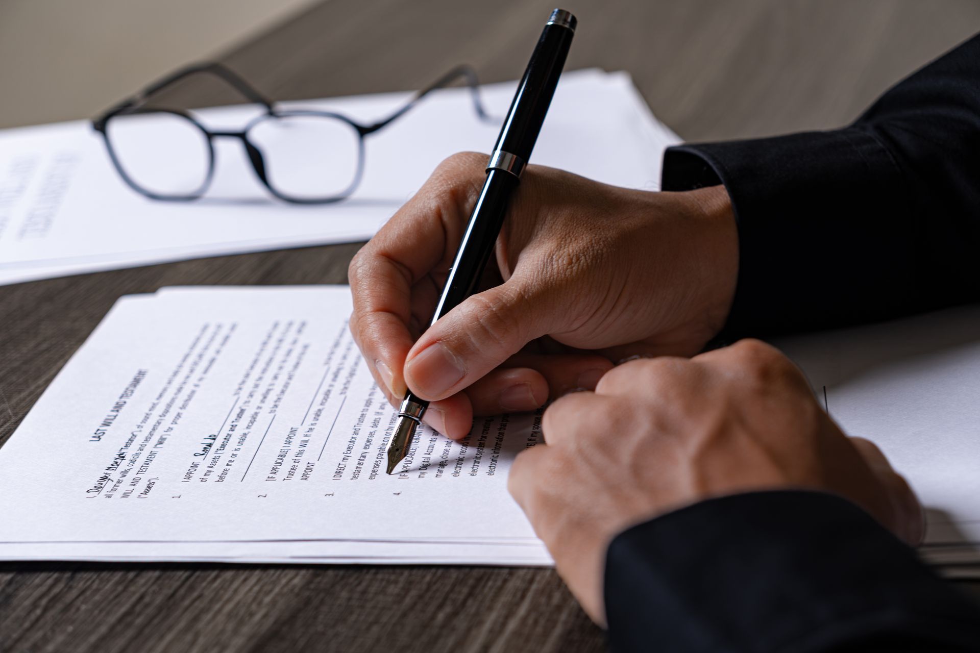 Signature manuscrite d’un document à côté de lunettes posées sur un bureau