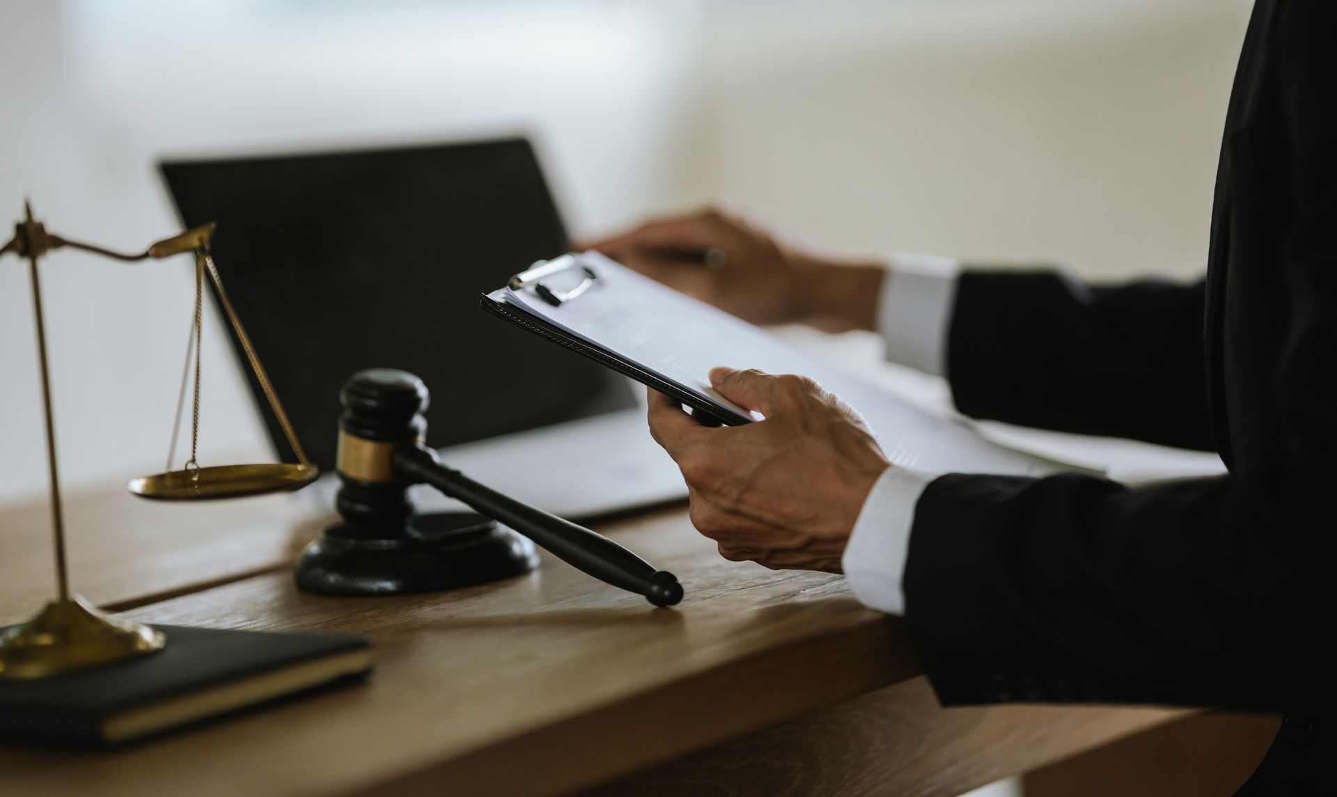 Avocat utilisant une tablette à son bureau, avec un maillet de juge et une balance de justice à proximité.