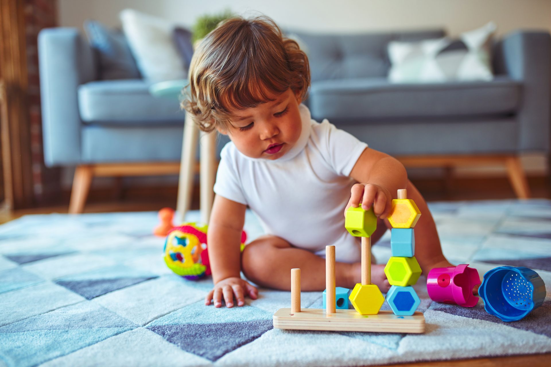 Un enfant joue avec des blocs colorés sur un tapis dans un salon.