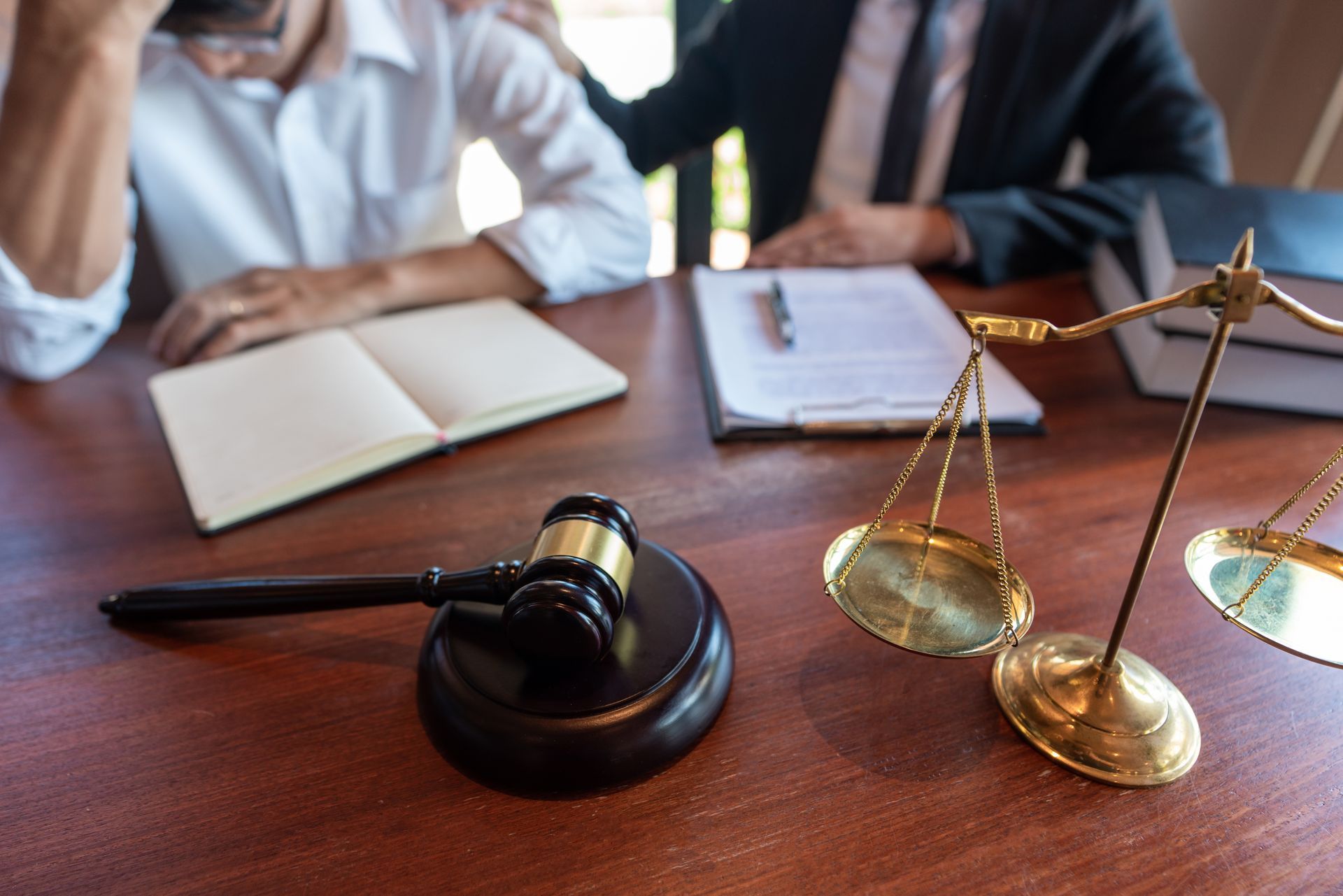 Livres de droit, marteau de juge et balance sur un bureau lors d’une réunion juridique.