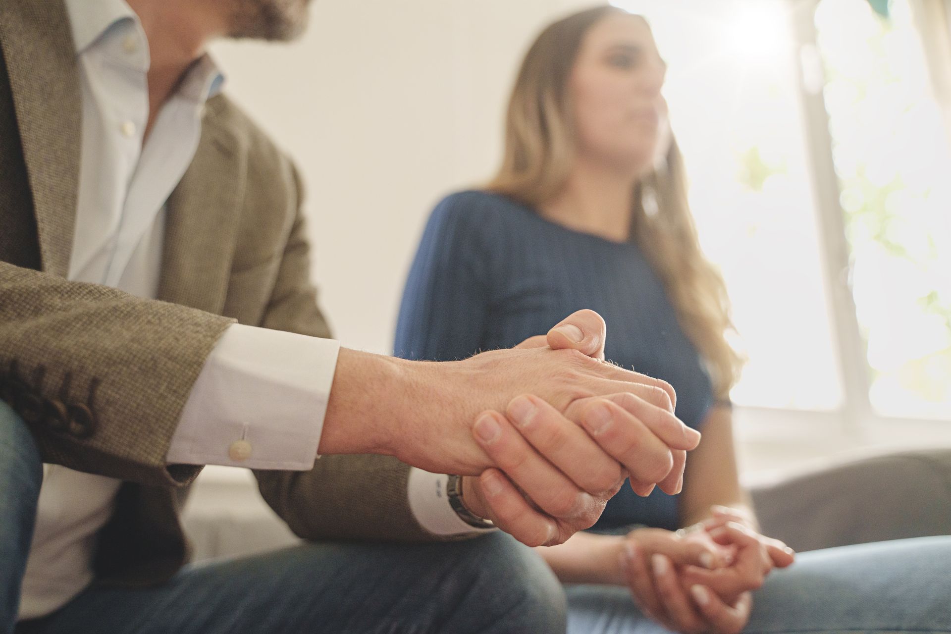 Deux personnes sont assises ensemble, l’une se tenant les mains, dans un cadre lumineux.