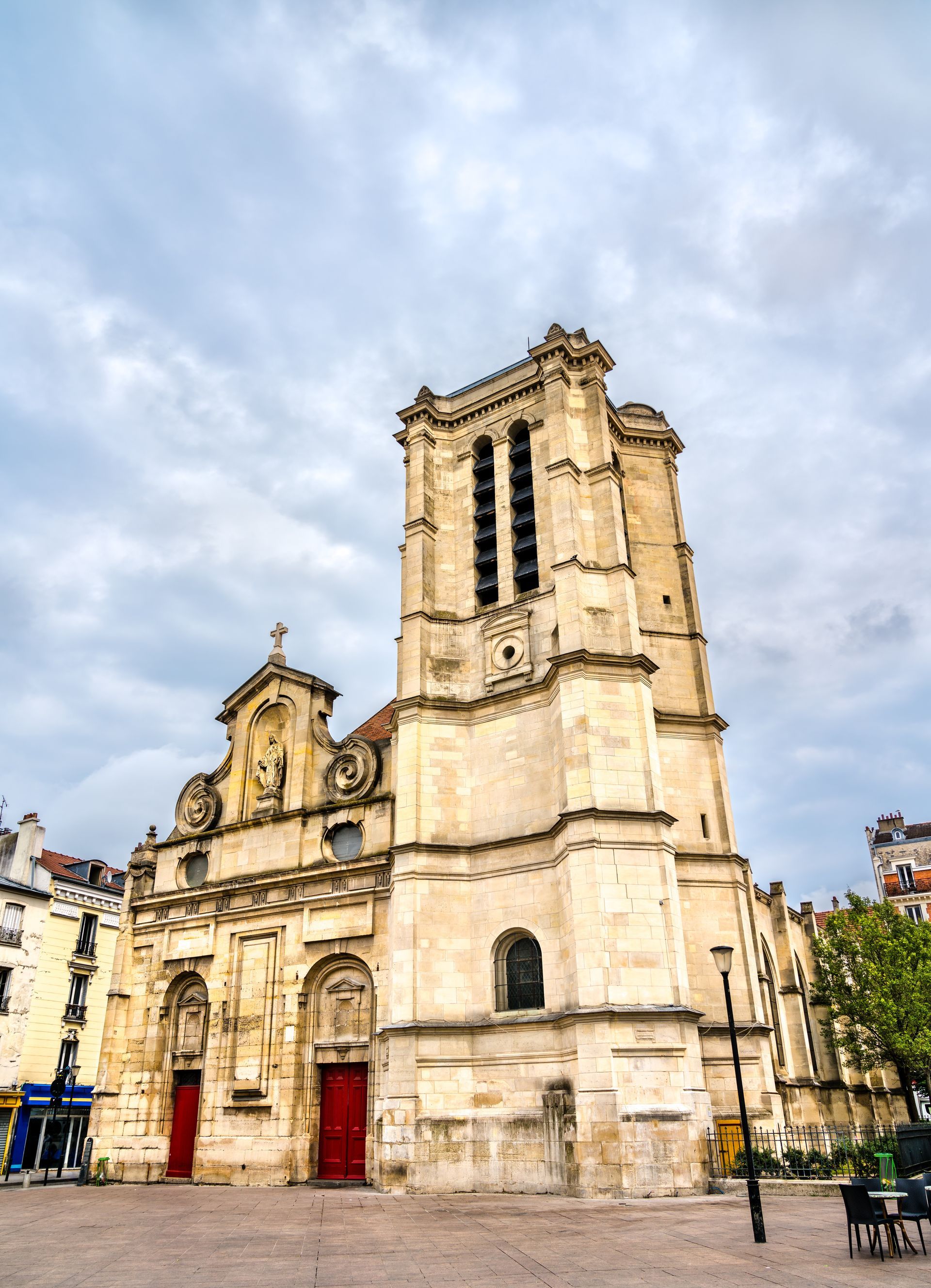 Église historique en pierre avec un haut clocher sous un ciel partiellement nuageux.
