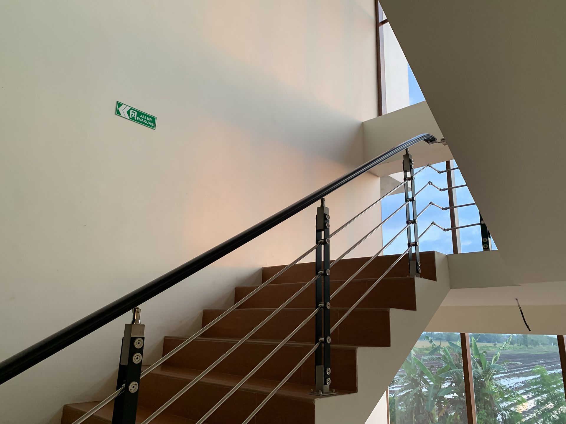 Un escalier moderne en bois avec une élégante rampe en métal noir.