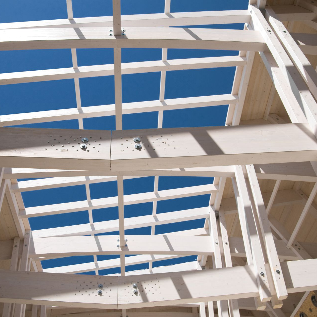 Vue en contreplongée d'une charpente de toit en bois blanc.