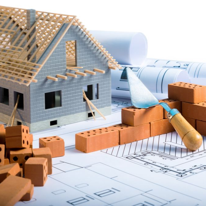 Une maison témoin en construction, un mur de briques et une truelle posée sur des plans architecturaux.