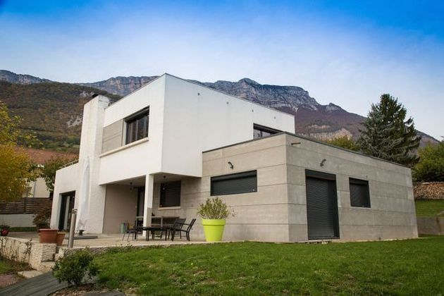 Une maison moderne de deux étages, blanche et en pierre.