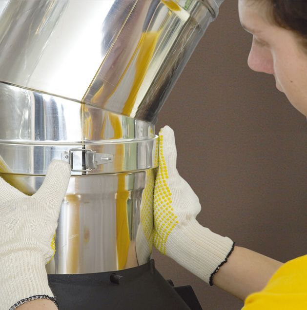 Un ouvrier ganté inspecte une machine métallique brillante dotée d'une chambre transparente.