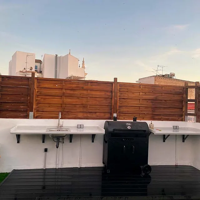 Hay una parrilla sobre una plataforma de madera al lado de un fregadero.