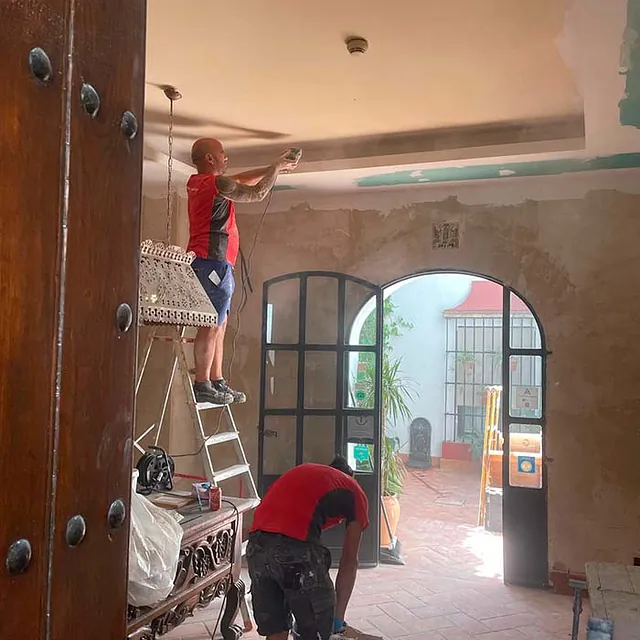 Dos hombres están trabajando en el techo de una habitación.