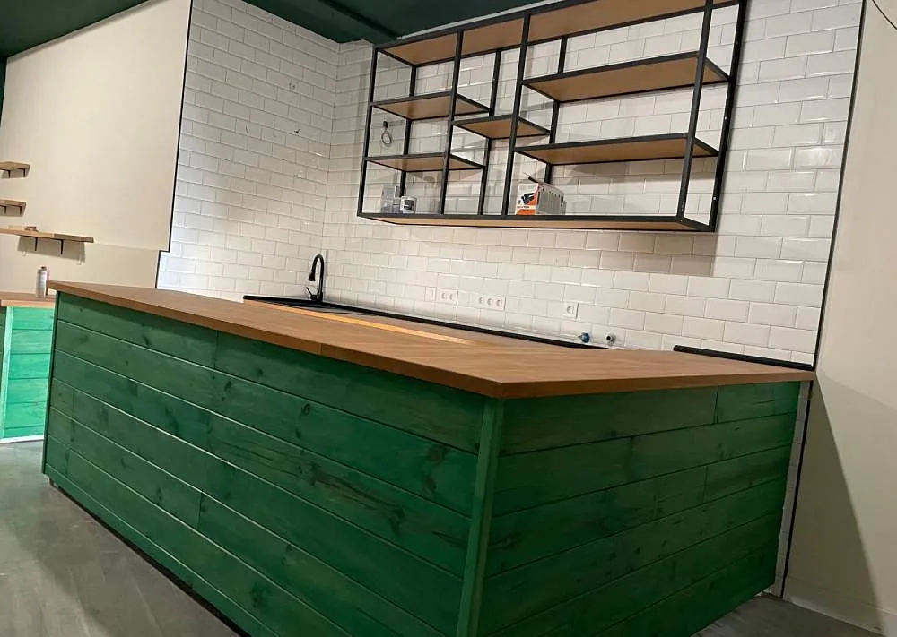 Una cocina con encimera verde y paredes de ladrillo blanco.