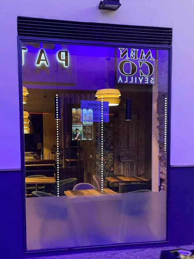 Un restaurante con mesas y sillas está iluminado con luces violetas.