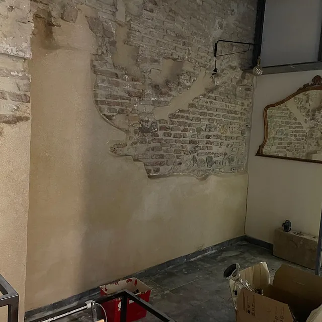 Una habitación con una pared de ladrillos y un espejo.