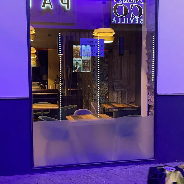 Un restaurante con mesas y sillas está iluminado con luces violetas.