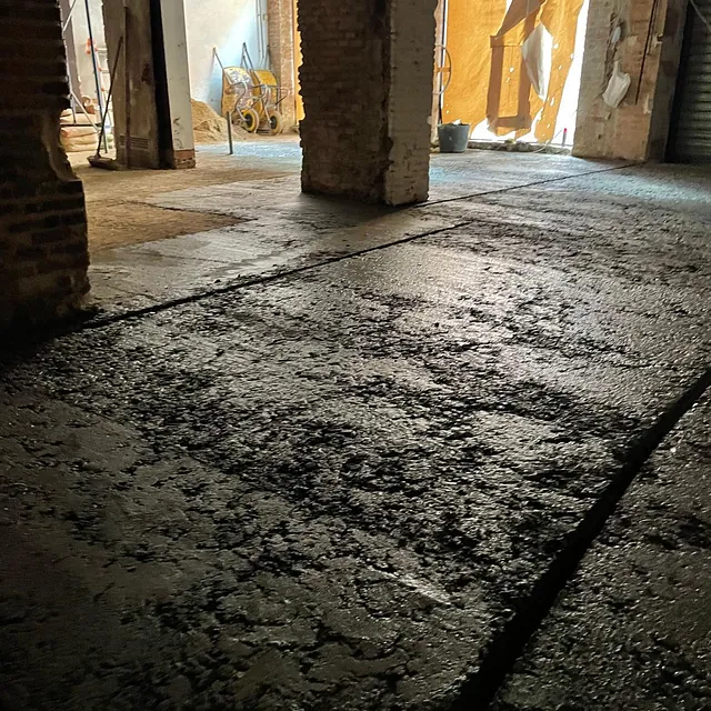 Un piso sucio con una pared de ladrillos al fondo.