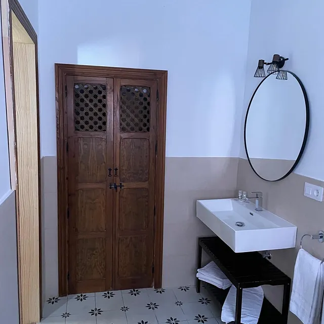 Un baño con lavabo y espejo redondo.