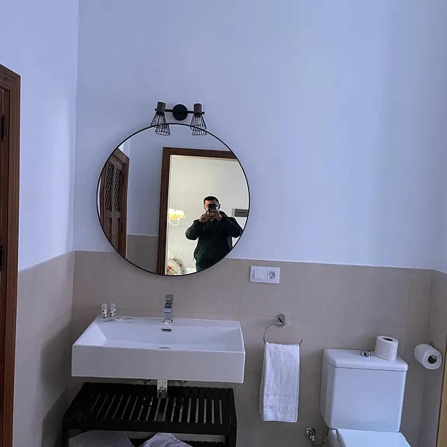 Un hombre se está tomando una foto en el espejo del baño.