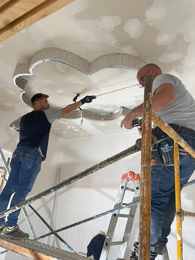Dos hombres están trabajando en un techo sobre un andamio.