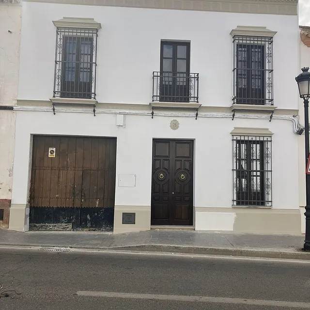Un edificio blanco con puerta de madera y balcones.