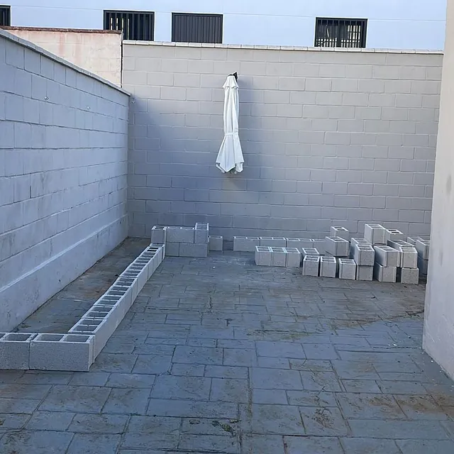 Una pared de ladrillos con un paraguas blanco colgando de ella.