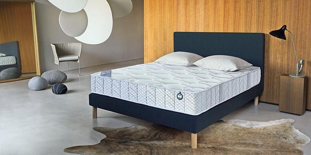 Chambre avec un sommier de couleur anthracite et un tapis en peau d'animal