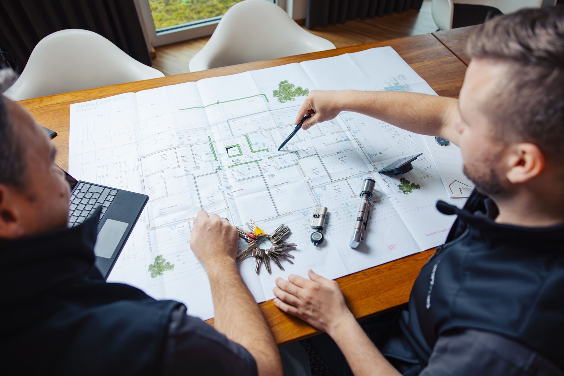 Architekten überprüfen Baupläne auf einem Computerbildschirm, zeigen auf Details und besprechen Projektpläne.