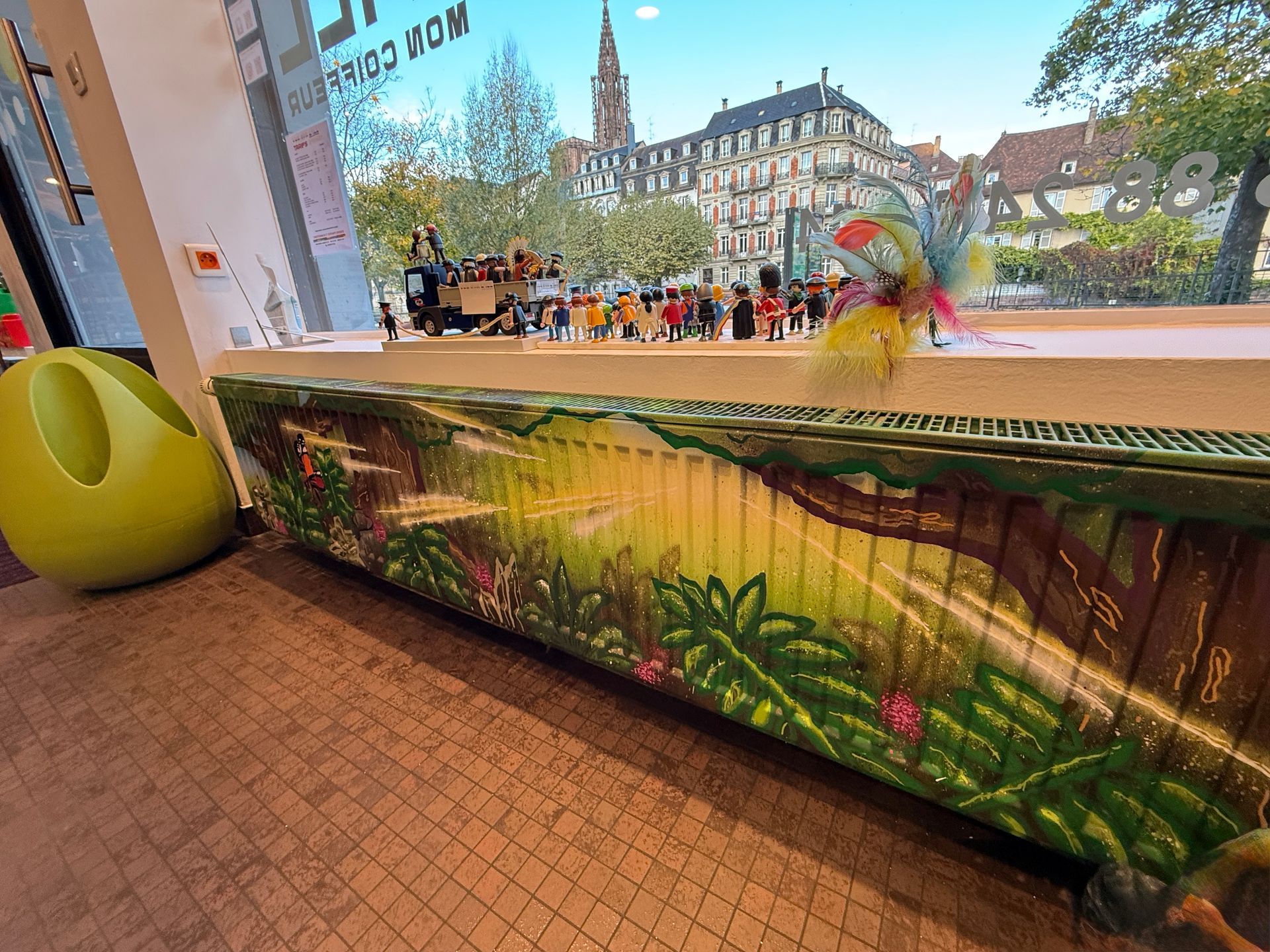 Peinture d'un autre radiateur sous une vitrine où trônent des Playmobil et un véhicule en jouet