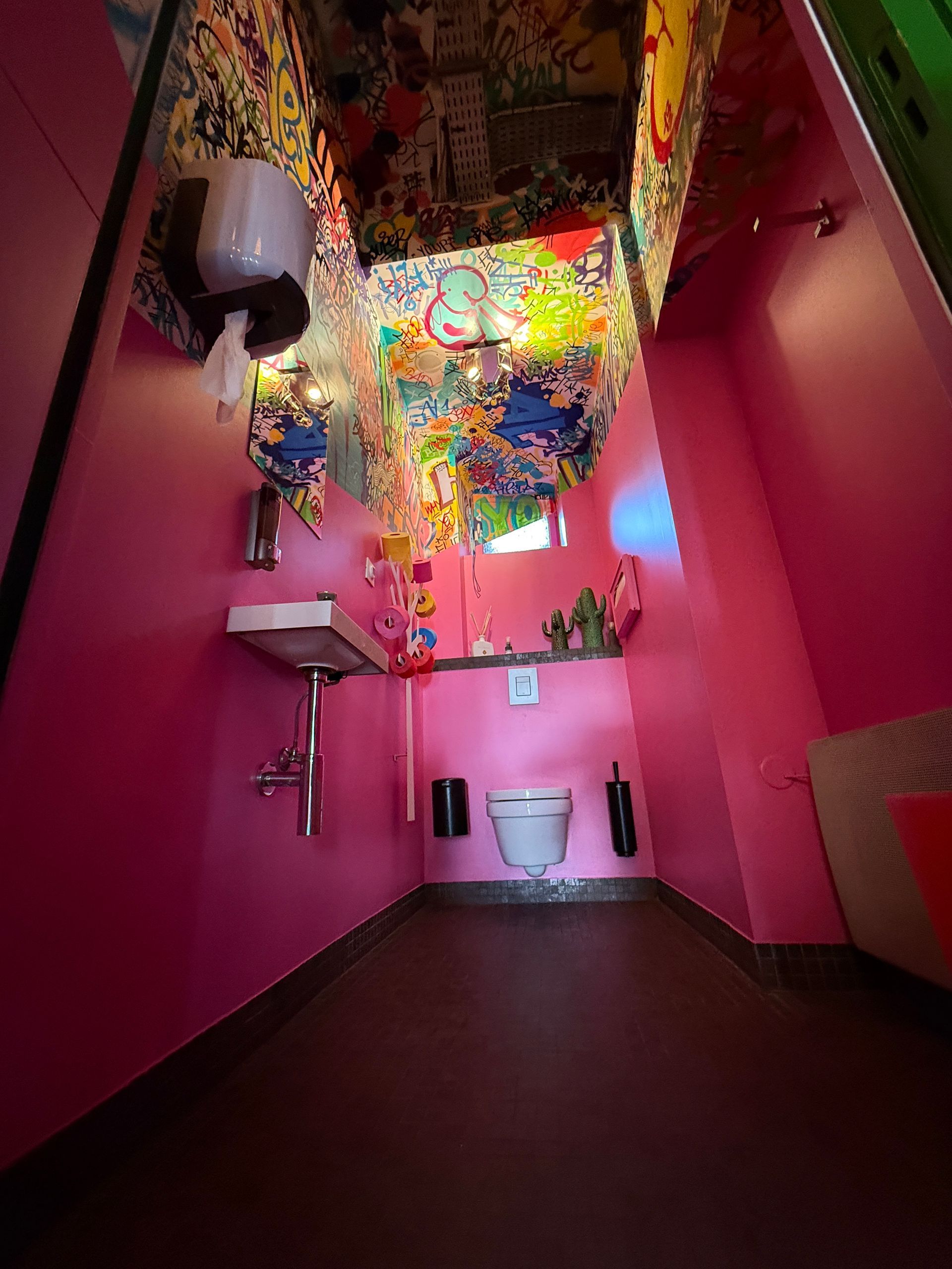 Vue en contre-plongée des toilettes montrant les graffitis en haut des murs et au plafond