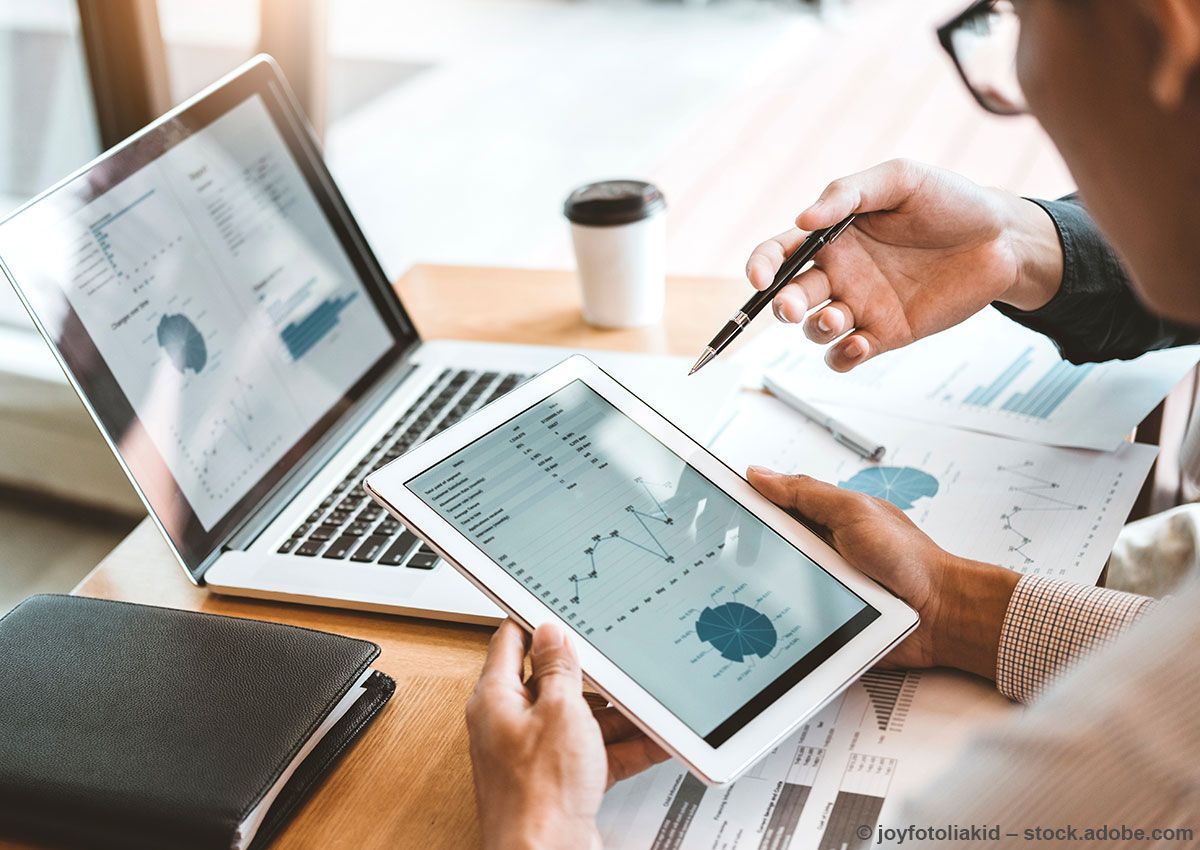 Frau im weißen Hemd schüttelt lächelnd in einem Büro die Hand.