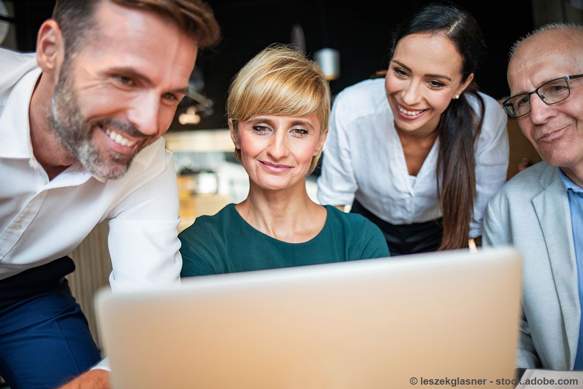 Frau im weißen Hemd schüttelt lächelnd in einem Büro die Hand.