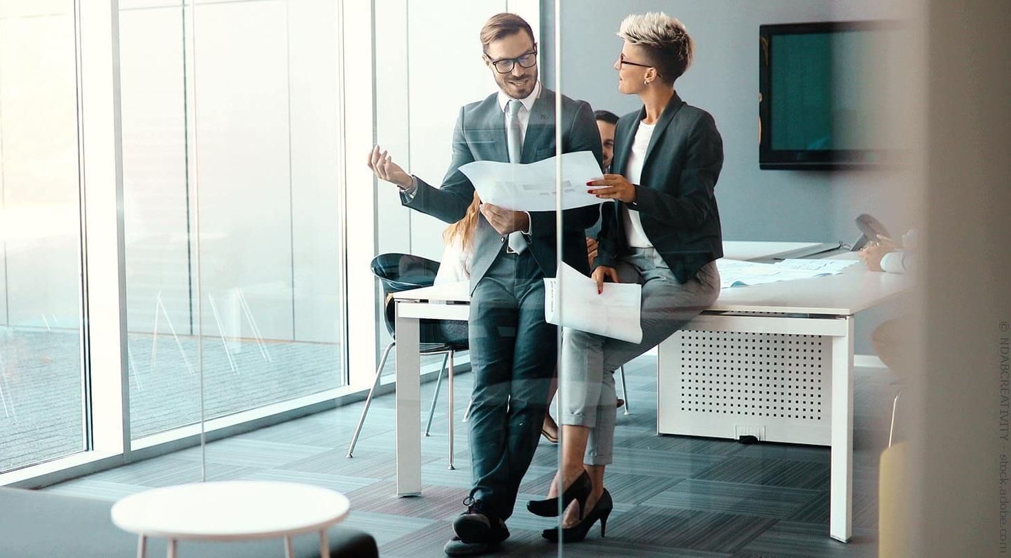 Frau im weißen Hemd schüttelt lächelnd in einem Büro die Hand.