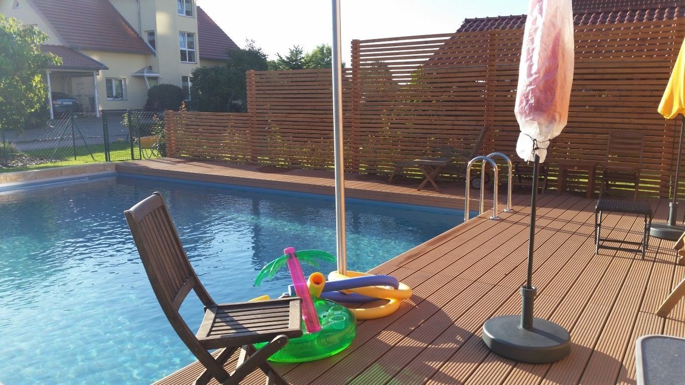 Naturpool mit Holzdeck und Gartenstühlen