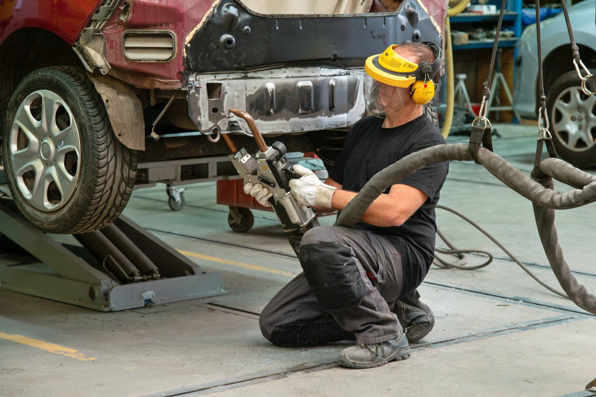 Technicien en intervention d'une voiture citadine rouge à l'arrière de son par choc desossé.