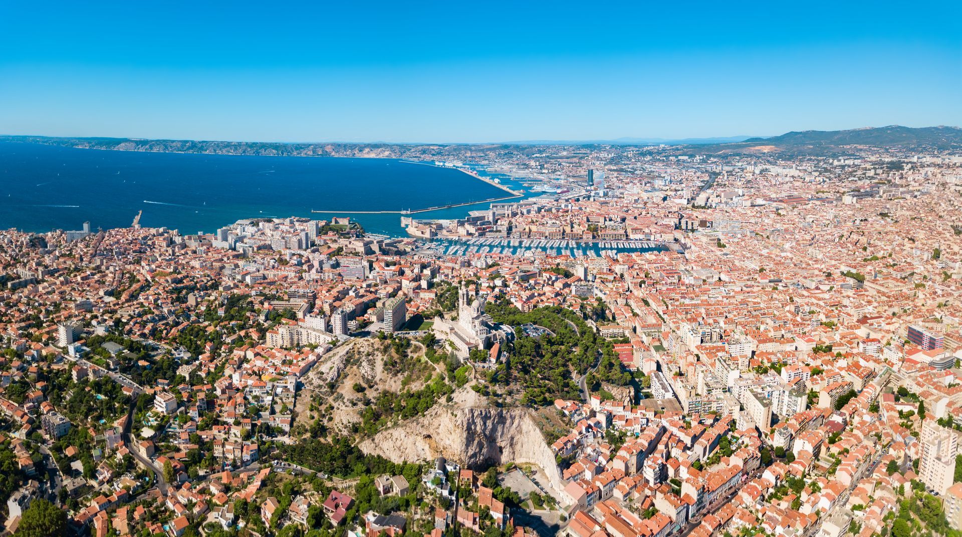 Vue aérienne de Marseille, en France, avec ses bâtiments, la mer et un ciel bleu dégagé.