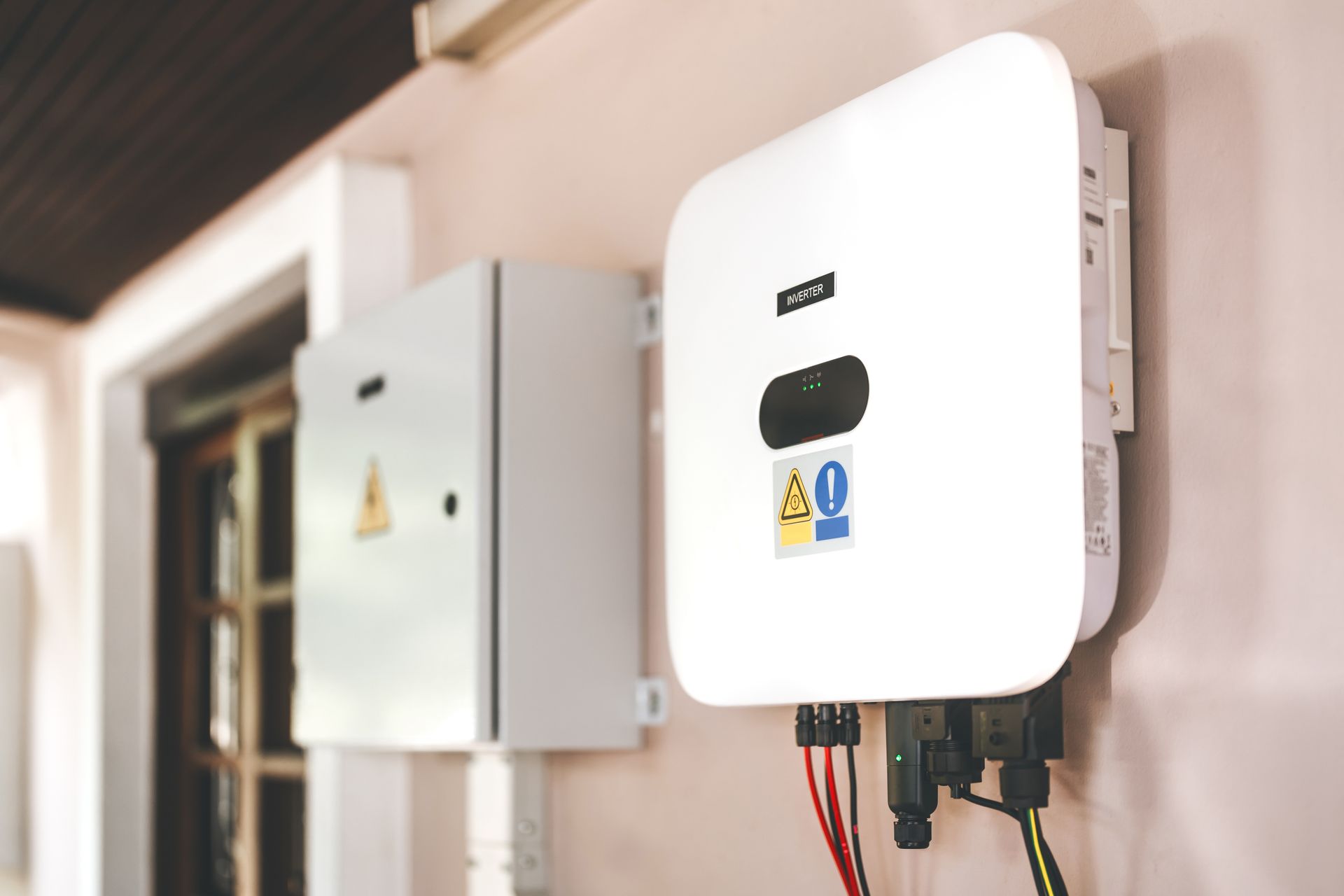 Onduleur solaire blanc monté sur un mur extérieur avec boîtier électrique.