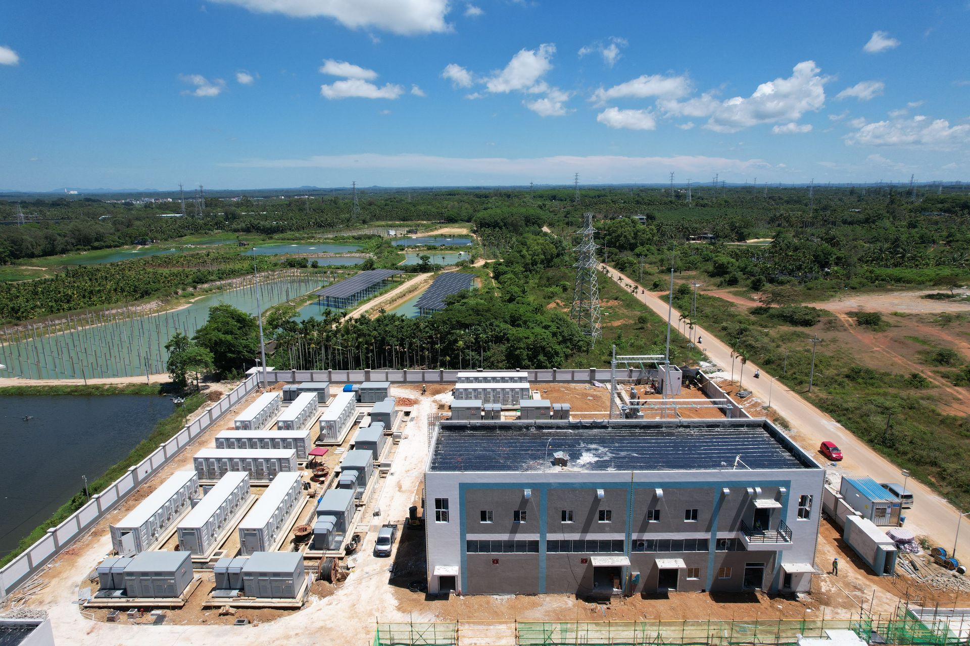 Vue aérienne d'une centrale électrique avec des panneaux solaires en arrière-plan et un ciel bleu.