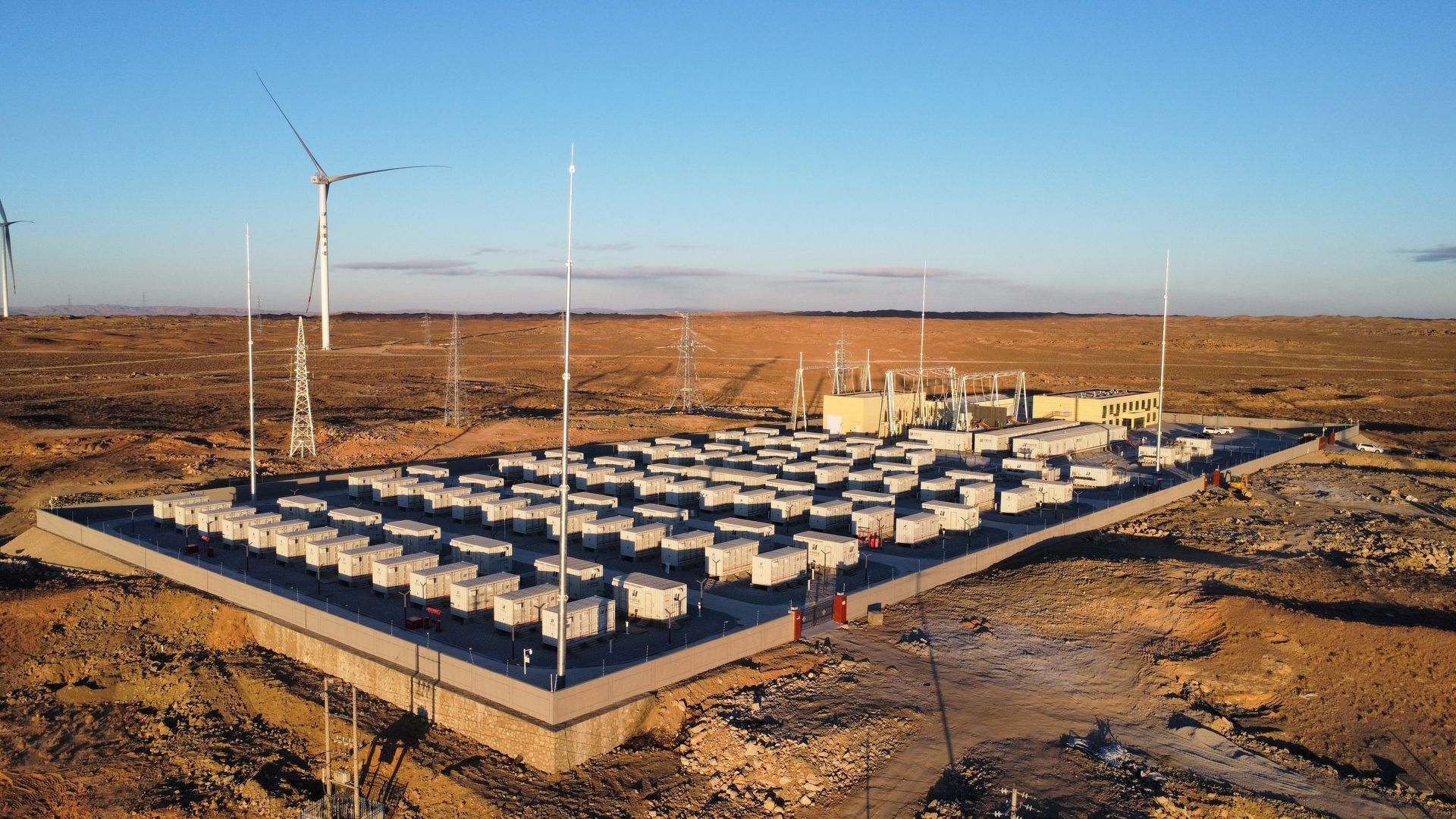 Centrale énergétique solaire et éolienne en milieu désertique, dotée de nombreuses unités de stockage par batteries.