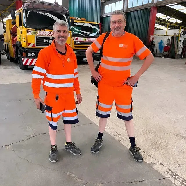 Dos hombres parados uno al lado del otro frente a un camión de transporte de personas.
